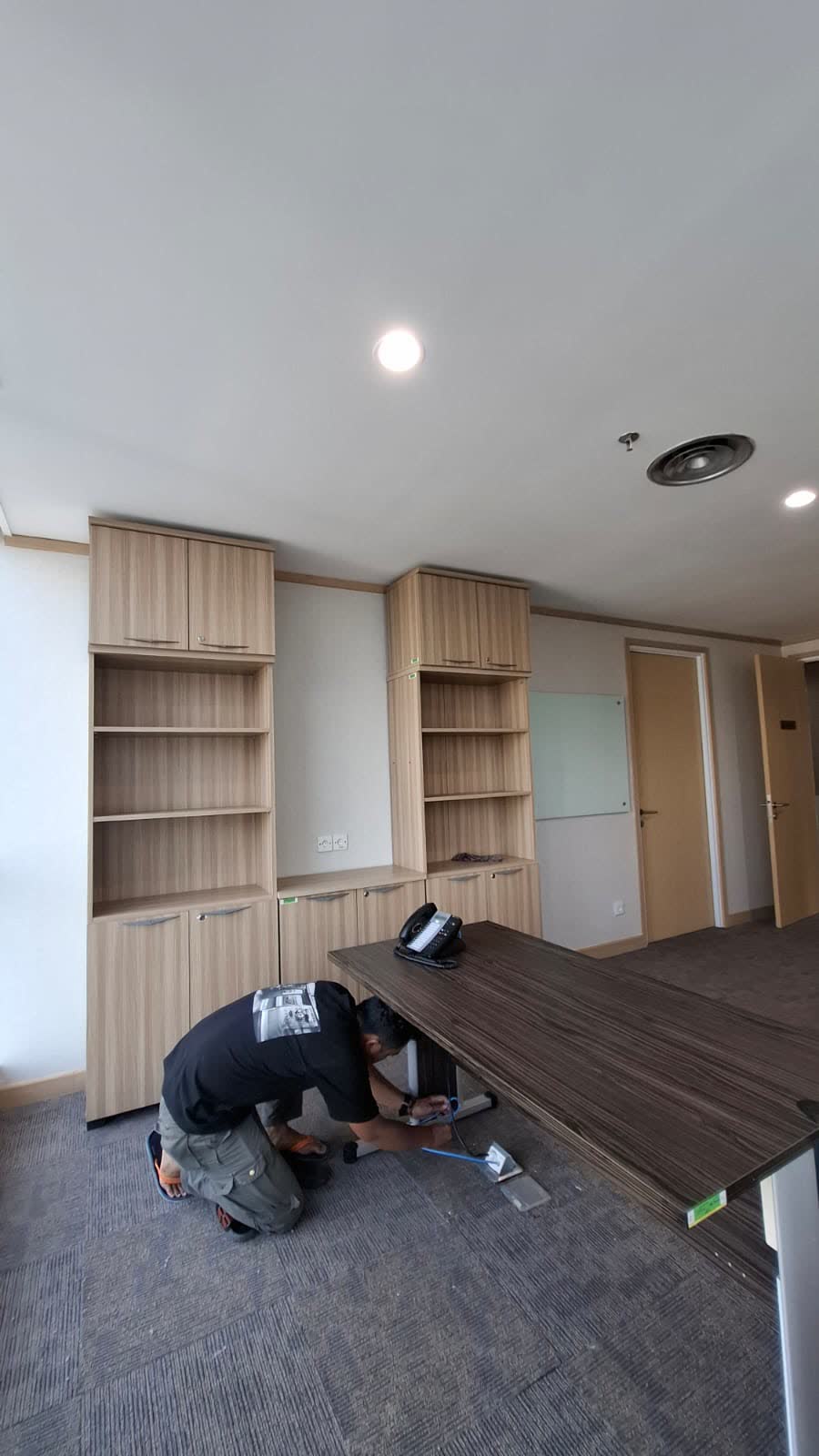 Tukang sedang memasang meja kerja dan kabel di ruang kantor
